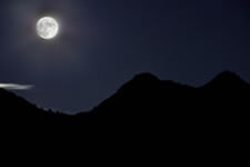 La luna fotografata come un oggetto illuminato dal sole (1/60 di secondo a f/11) ha reso del tutto illeggibile il paesaggio terrestre: le montagne appaiono qui come una nera silhouette. Il bagliore colorato intorno al satellite è dovuto all'umidità presente nell'atmosfera.