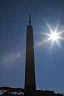 L'obelisco di piazza San Pietro in controluce, fotografato con zoom 24-105mm e filtro di protezione (bella protezione!). Le immagini fantasma del foro del diaframma sono dovute certo allo schema ottico complesso dello zoom, ma anche alla presenza del filtro (tranquilli, la foto ha un semplice intento didattico, di sicuro non è di quelle che mando in giro!).