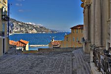 La piazzetta antistante la basilica di San Michele Arcangelo. I ciottoli della pavimentazione riproducono lo stemma dei Grimaldi (ricordiamo che la città appartenne al Principato di Monaco dal 1346 al 1848). Iniziata nel 1640, la basilica fu più volte rimaneggiata. Sul sagrato si tiene l’annuale Festival de Musique (agosto).